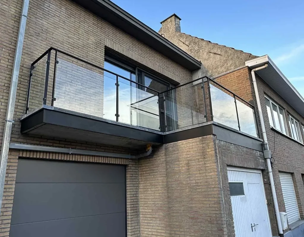 Balcon métallique en porte-à-faux avec garde-corps en verre et structure acier noire, réalisation Metal Hanart au-dessus d'un garage