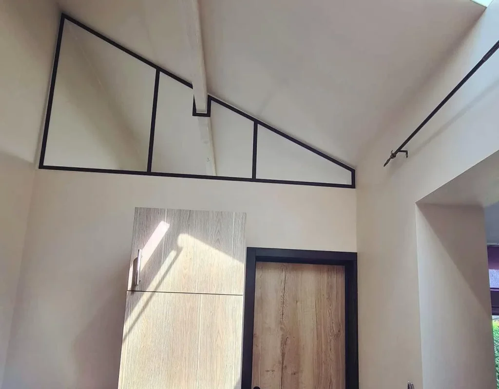 Verrière métallique sur mesure en imposte triangulaire suivant la pente de toiture, réalisation Metal Hanart avec poutre apparente